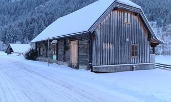 A charming wooden house in the snow, surrounded by snow-covered mountains. The winter landscape creates a calm and peaceful atmosphere.