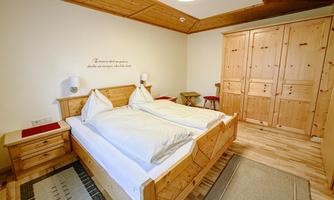 A cozy bedroom with a wooden double bed and a wardrobe. The walls are light, and the furniture conveys a warm, inviting atmosphere.