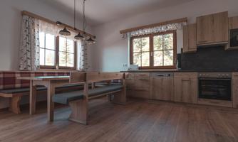 Modern kitchen with wooden furniture and space for dining. Large windows let in plenty of light.