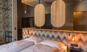 A modern room with two beds and stylish wooden decor. The walls are designed with an interesting pattern and there is soft lighting.