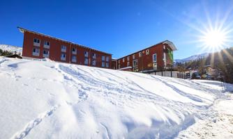 A modern building in a snow-covered landscape. The sun is shining brightly in the blue sky.