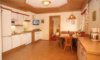 A bright kitchen with modern appliances and a dining area. The wooden elements give the room a cozy atmosphere.