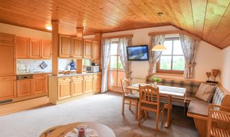 A cozy living space with a modern kitchen and dining area. Large windows provide plenty of daylight and a welcoming atmosphere.