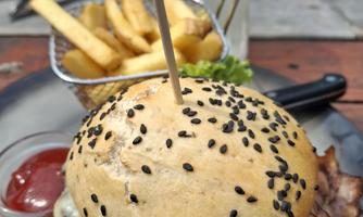 A delicious hamburger with a black sesame bun, lettuce, and cheese. It comes with crispy fries and ketchup.