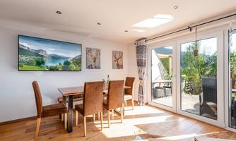 A cozy dining area with a wooden table and chairs. Large windows provide plenty of natural light and a view of the outdoors.