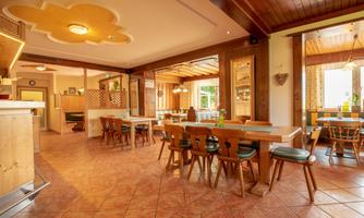 An inviting restaurant with wooden furniture and a cozy atmosphere. Large windows let in plenty of light and offer a view of the surroundings.