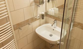 A modern bathroom with a shower, a sink, and a towel holder. The walls are brightly tiled and the furnishings are simple and functional.