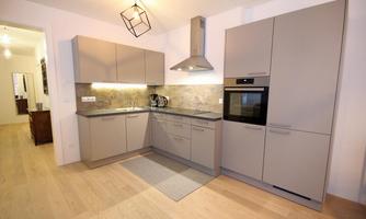 A modern kitchen with gray cabinets and stainless steel appliances. The room is bright and friendly, with elegant lighting.