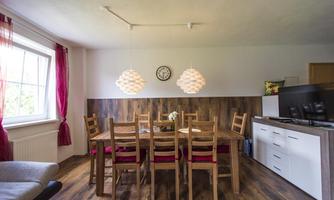A cozy dining area with a large wooden table and eight chairs. The modern lamps and warm wood create an inviting atmosphere.