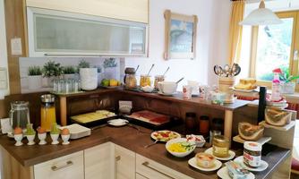 An inviting breakfast corner with various foods and drinks. On the counter, there are fresh rolls, fruit, and eggs in egg cups.