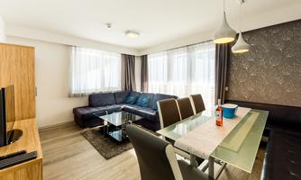 A modern living room with a cozy sofa and an elegant dining table. Large windows let in plenty of light and create an inviting atmosphere.