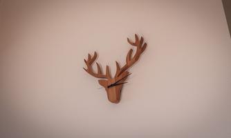 A wall clock in the shape of a deer head made of wood. The antlers are stylishly designed and add a rustic charm to the room.