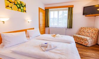 A cozy room with two single beds and a bright, inviting atmosphere. A seating area and a window overlooking the outside complete the picture.
