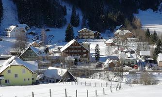 A snowy village with idyllic houses and beautiful mountains in the background. The landscape is calm and wintry.