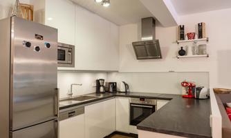 A modern kitchen with white cabinets and a stainless steel refrigerator/freezer combination. It is well-equipped with various kitchen appliances and has an inviting atmosphere.