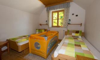A simple room with two single beds and a children's bed. The room has a window that lets in daylight.