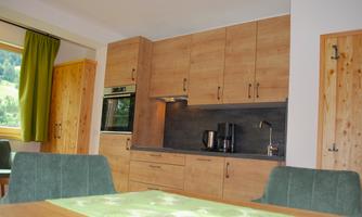 A modern kitchen with wooden cabinets and an elegant countertop. The room is bright and friendly, with a dining table and chairs.