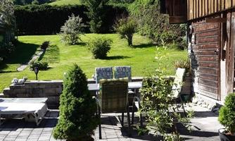 A beautiful garden with lawns and plants. A seating area with tables and chairs invites you to relax.
