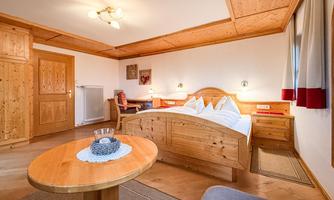 A cozy room with wood paneling and a large bed. The space is brightly and warmly furnished.