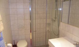 A modern bathroom with a glass shower and bright tiles. The amenities include a sink and a toilet.