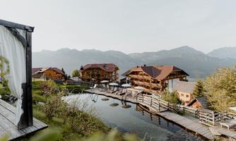 A picturesque mountain landscape with charming wooden houses by the water. Relaxing atmosphere with wooden walkways and sun umbrellas.
