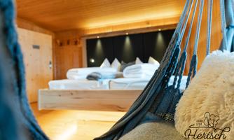 A cozy room with a hanging chair and a modern bed in the background. The wooden paneling creates a warm and inviting atmosphere.
