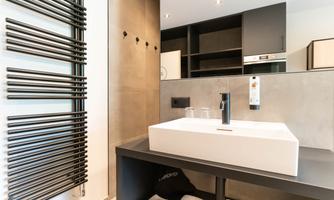 A modern bathroom with a simple white vanity and a stylish towel warmer. The walls are in neutral colors, creating a calm atmosphere.