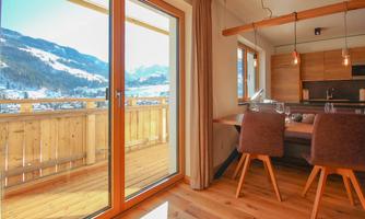 A modern apartment with a dining area and a view of the mountains. Large windows let in plenty of daylight.