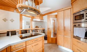 A modern kitchen with wooden furniture and stainless steel appliances. The space is flooded with light and designed to be inviting.