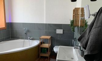 A modern bathroom with an oval bathtub and elegant sink. The gray tiles and wood details give the space a stylish atmosphere.