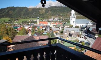 A picturesque view of a village in the Alps with traditional houses and a church. Majestic mountains can be seen in the background.