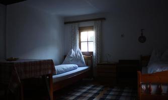 A cozy bedroom with two beds and a table. The light gently falls through the window, which is adorned with curtains.