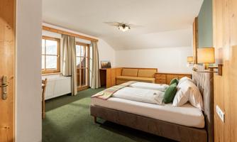 A cozy hotel room with a double bed and a seating area. Large windows provide plenty of natural light and a pleasant stay.