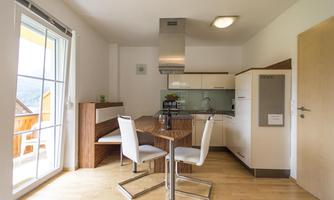 Bright and modern kitchen with a dining area. Large windows provide a view outside and plenty of daylight.