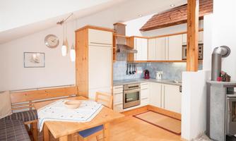 A bright and modern equipped kitchen with wooden details. The dining area is cozy with a table and chairs.