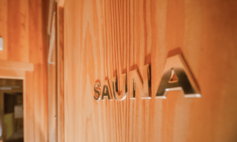 A wooden wall with a shiny inscription "SAUNA". The atmosphere is warm and inviting.