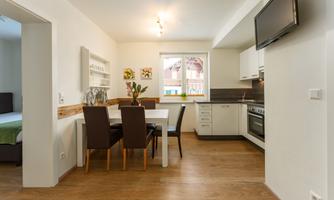 A modern kitchen with a dining area. The space is bright and welcoming, with a table and matching chairs.