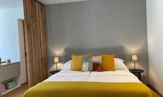 A modern bedroom with a large bed and colorful pillows. On both sides of the bed, there are small table lamps.