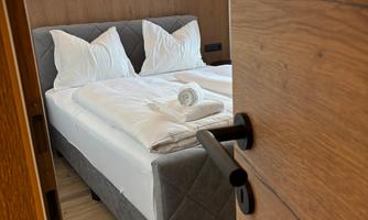 A cozy bedroom with a large bed and attractive bedding. A decorative mountain motif and warm lighting hang on the wall.