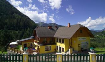 A charming yellow house amidst a picturesque mountain landscape. The sky is clear and nature surrounds the building.