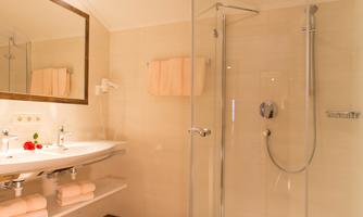 A modern bathroom with a glass shower cabin and a bright, friendly ambiance. The wooden floors and soft color tones create an inviting atmosphere.