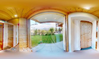 A bright interior with wooden paneling and large windows. Outside, there is a well-kept garden and mountain view.