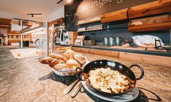 A buffet with various rolls and a dish in a pan. The surroundings are modern and inviting.