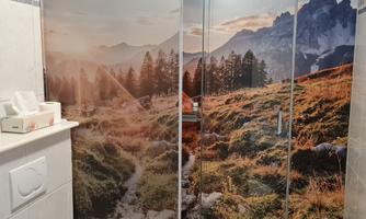 A shower enclosure with a beautiful landscape motif of mountains and forests. The background features a picturesque mountain scenery in warm colors.