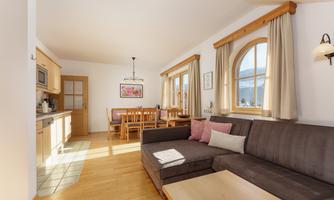 A bright living room with a comfortable couch and a dining area. Large windows let in plenty of light and give the room a cozy atmosphere.