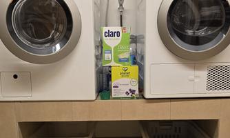 A modern laundry room with two washing machines. In the middle are detergents and laundry baskets.