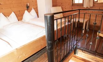 A cozy wooden ceiling with a sleeping area and a table on the ground floor. There is plenty of light and a rustic atmosphere.