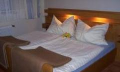 A cozy bedroom with a double bed and large pillows. The warm lighting creates an inviting atmosphere.