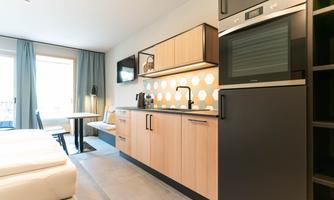 A modern kitchen corner with wooden cabinets and cooking appliances. The room has lots of daylight and an inviting atmosphere.