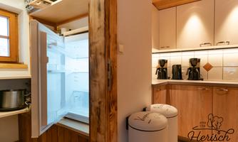 A modern kitchen with an open refrigerator and two coffee machines. The wood and white elements give the kitchen a cozy atmosphere.